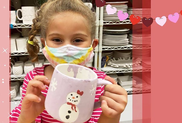Girl holding snowman mug at arts and crafts studio Amaze In Pottery