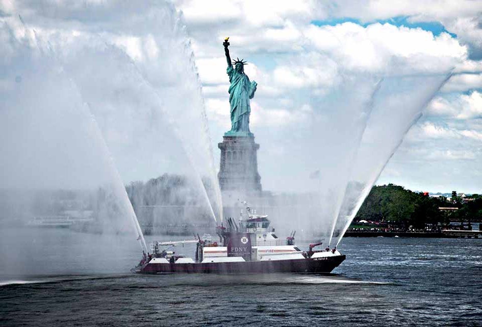 A New York City Fire Department vessel honors the Statue of Liberty with a water salute for Fleet Week. Photo courtesy of Fleet Week New York