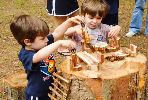 Photo of kids playing together with wooden toys in a playground.