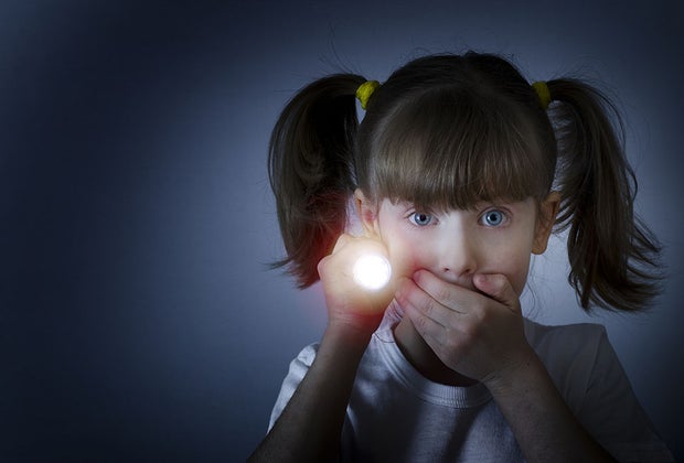 girl looking quiet while holding flashlight in the dark