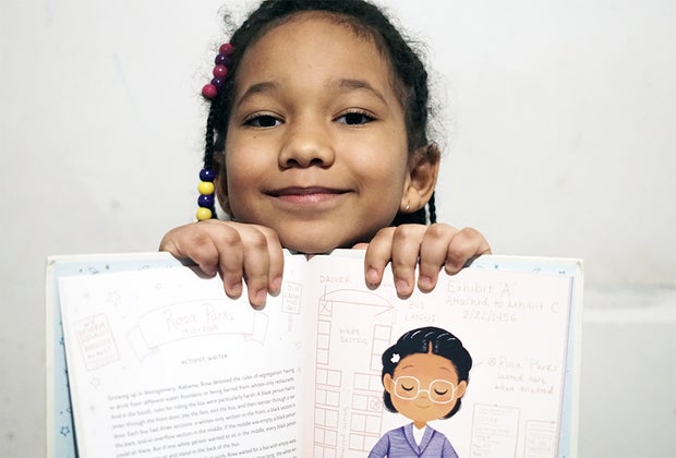 Girl holding up book black history book Ada Twist Scientist