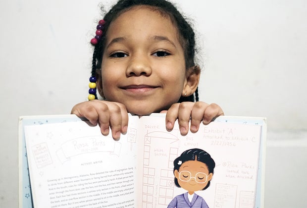 Girl holding up book black history book Ada Twist Scientist