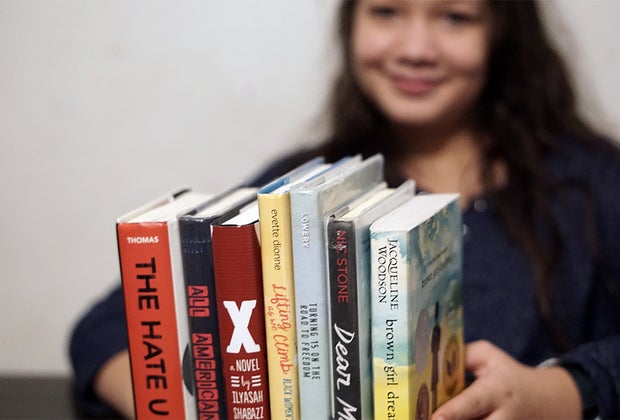 Girl holding a stack of book on Black History for Teens and young adults