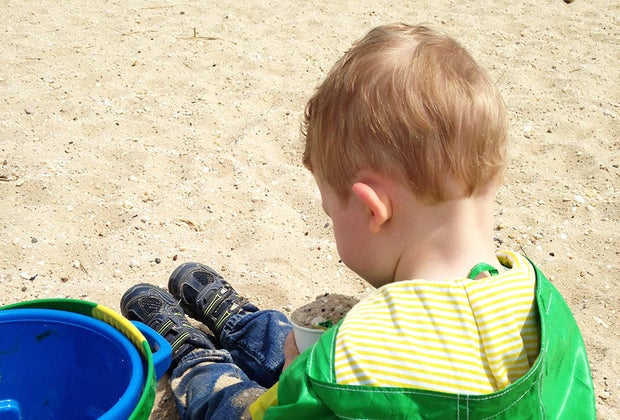 Hiking Games for Kids That Turn Walks into Adventures: kid playing in the sand with a bucket
