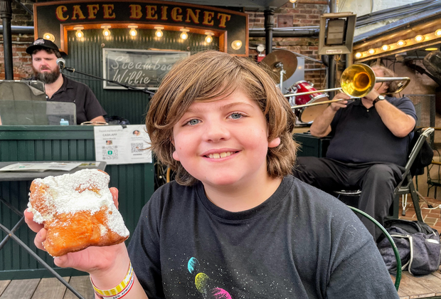 kid holding up beignet from Cafe Beignet in New Orleans
