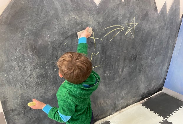 Boy drawing on chalk wall at The Kiddie Clubhouse