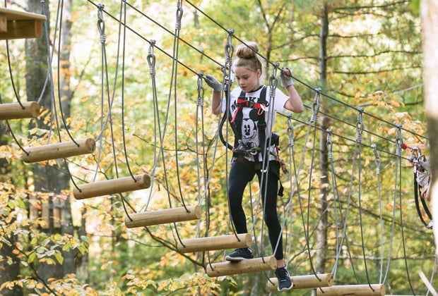 Image of a child on a tree-top rope bridge.