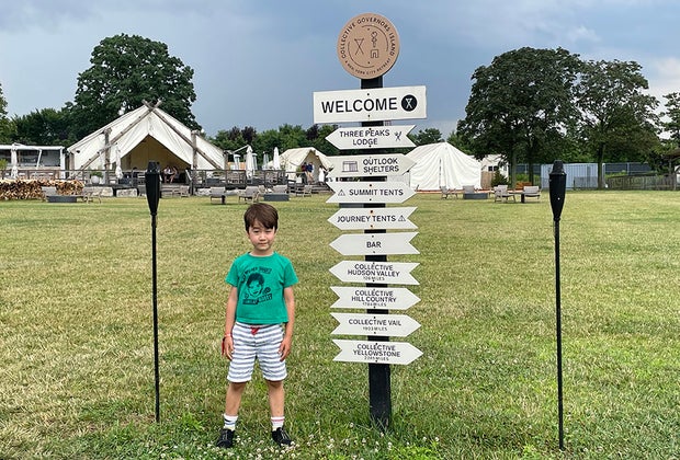Little boy in front of camp sign at Collective Governors Island