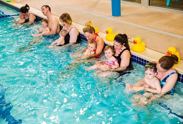 moms and dads and babies in pool for swim class