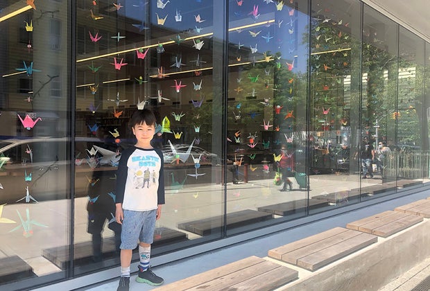 Child in front of windows that are covered in artwork greenpoint library