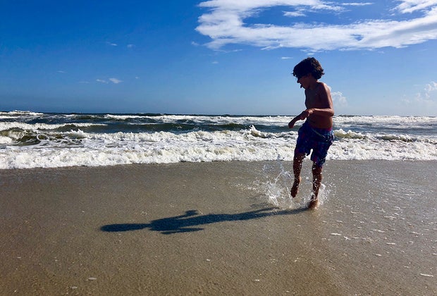 guide to the Hamptons with Kids: Beach day child playing in the ocean