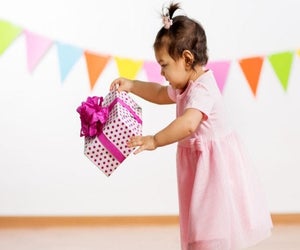 picture of a baby with a wrapped birthday gift photo by canva