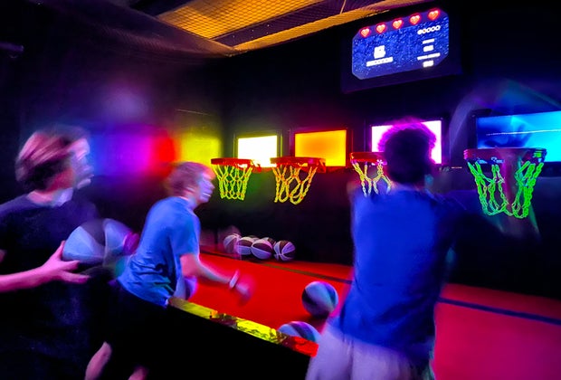 Teens playing a shooting game at Activate, neon, arcade, sports