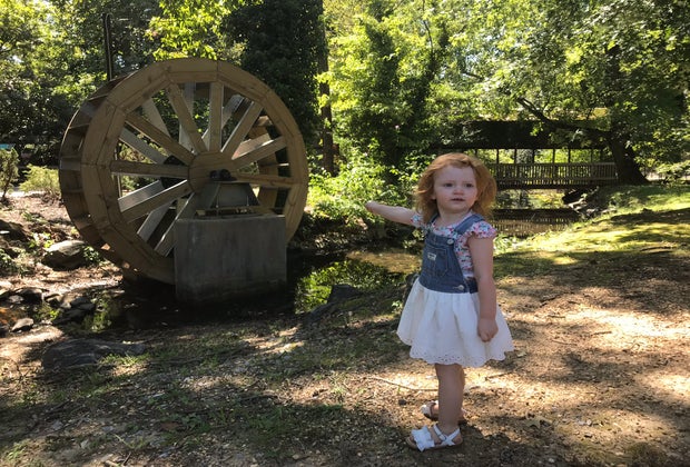 girl standing near water wheel at zoo