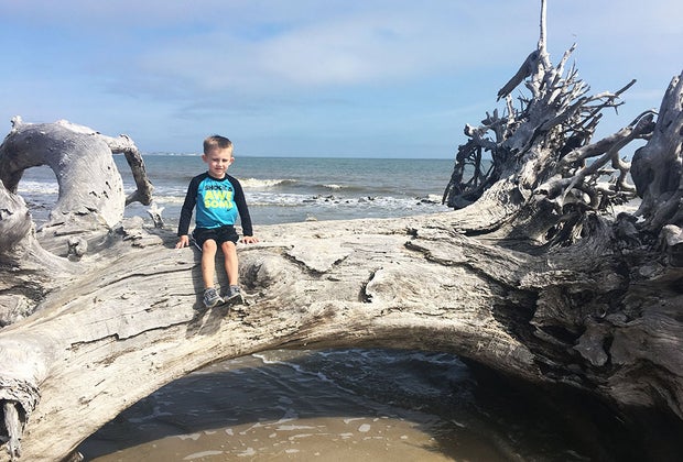 boy sitting on log at the ocean at Jekyll Island