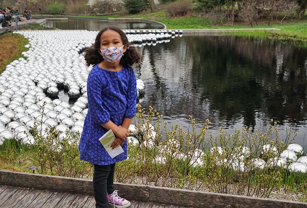 Girl standing near Kusama's Narcissus Garden in the Native Plant Garden at NYBG collection 1,400 stainless steel spheres