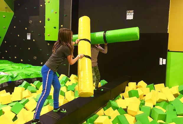 kids battling with foam on a balance beam
