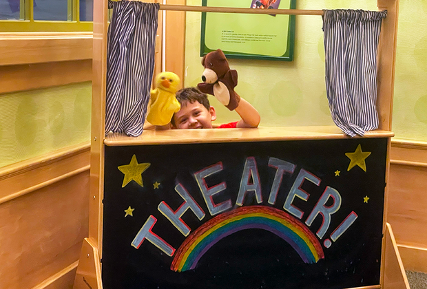 Exploring the Children's Museum of the East End: boy playing in puppet theater