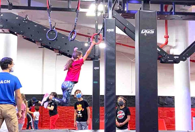 girl swings across rings at New York Ninja Academy