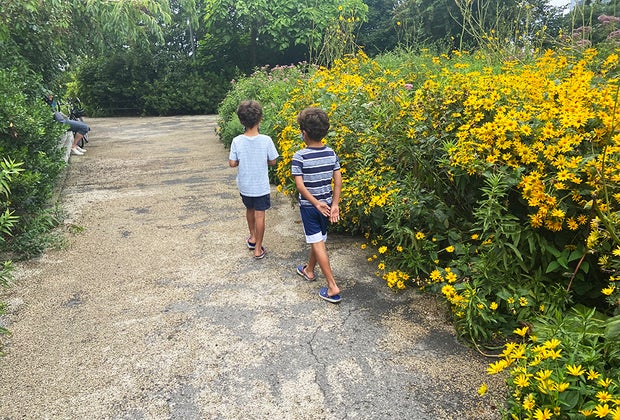 Outdoor Activities in Nature for Kids: 2 kids walking by a pollinator garden