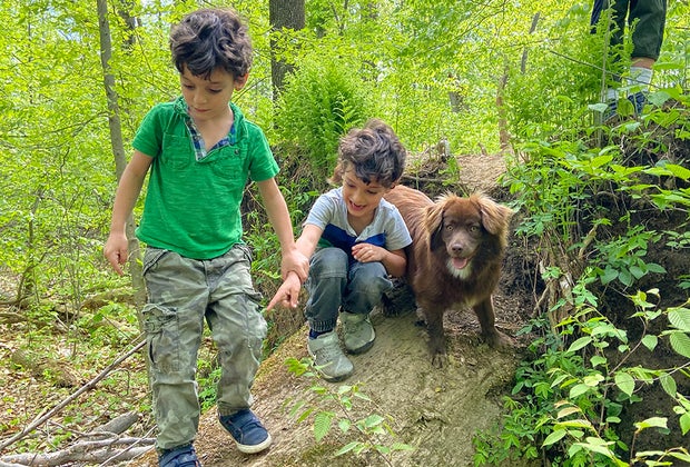 Outdoor Activities in Nature for Kids: two kids and a dog hiking in the woods