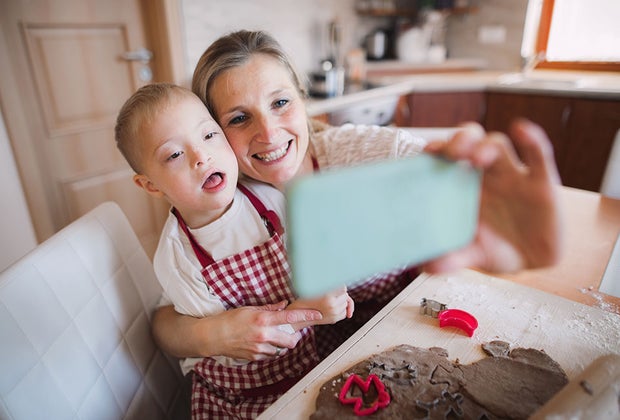 Mom and young spacial needs child take selfie while baking, as they enjoy every moment together.
