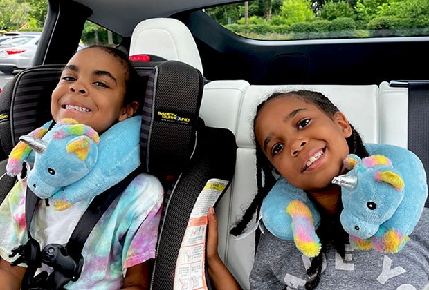 two girls in a car with unicorn neck pillows