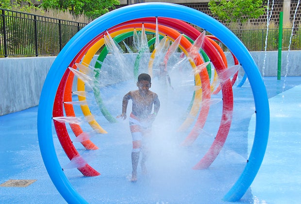Splash pads in NYC: Boy running though tunnel of water at Roberto Clemente State Park