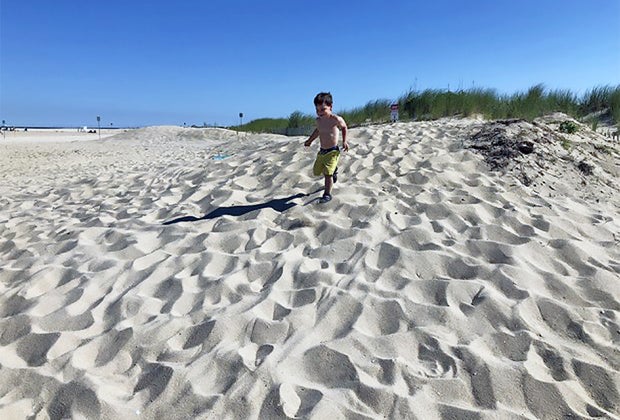 child plays on the dunes at Sandy hook National Seashore.