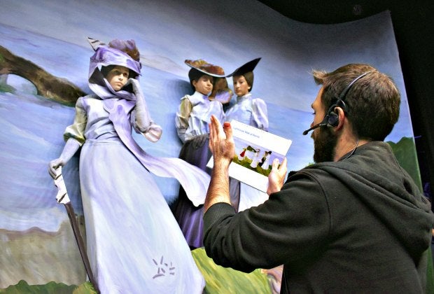 A pageant sculptor helps volunteer cast members into their poses at a rehearsal