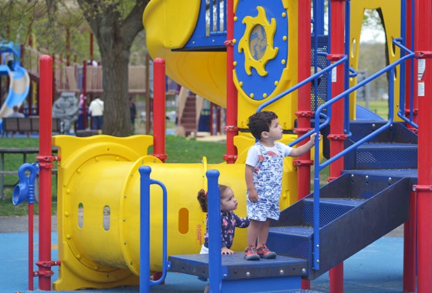 Two toddlers climb stairs on playground.