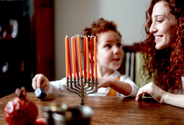 Child lighting candles for Hanukkah on a menorah