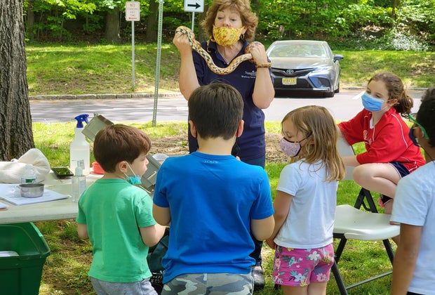 Masked kids looking at a women holding a snake