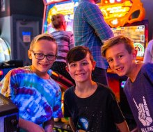 Three boys having fun at an arcade. Photo courtesy of Laser X in Addison