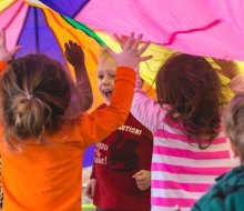 Kids under a parachute. Photo courtesy of the Purple Monkey Playroom