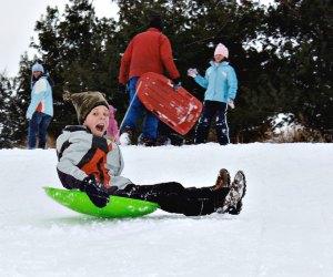 Child sledding on Danehy Park, one of the best sledding hills around Boston.