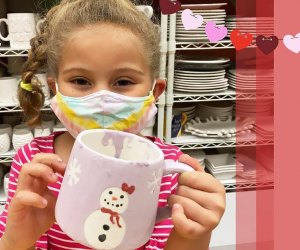 Girl holding snowman mug at arts and crafts studio Amaze In Pottery