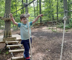 Little boy crosses rope bridge at The Adventure Playground