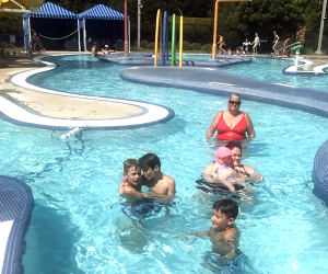 kids and adults swim in a lazy river pool area