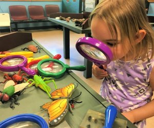 Photo of girl with magnifying glass at indoor play space in CT.