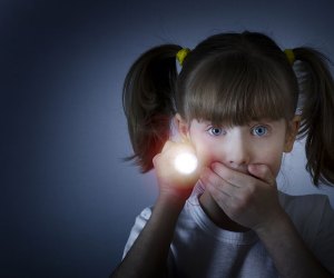 girl looking quiet while holding flashlight in the dark