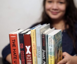 Girl holding a stack of book on Black History for Teens and young adults