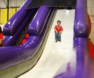 Boy sliding down a bouncy slide at BounceU, a trampoline park near NYC