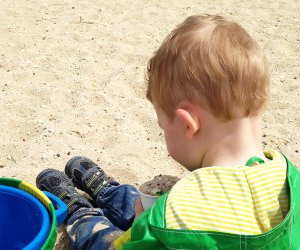 Hiking Games for Kids That Turn Walks into Adventures: kid playing in the sand with a bucket 
