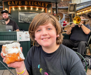 kid holding up beignet from Cafe Beignet in New Orleans