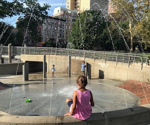 Girl perched on edge of water feature in Central Park's Tarr Family Playground