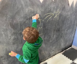 Boy drawing on chalk wall at The Kiddie Clubhouse