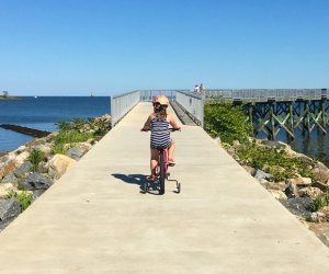 Photo of girl on a bicycle at a Connecticut state beach path.
