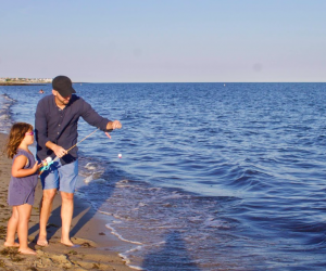 Photo of father and daughter fishing on a Cape Cod beach.