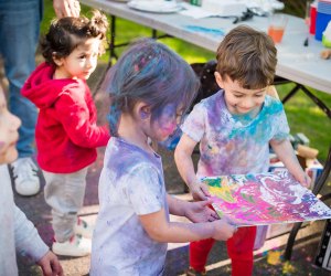 kids are grinning as they are doused head to toe in colors to celebrate Holi